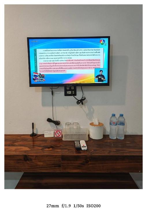 ein Fernseher an der Wand mit einem Holztisch in der Unterkunft king s hotel in Mae Sot