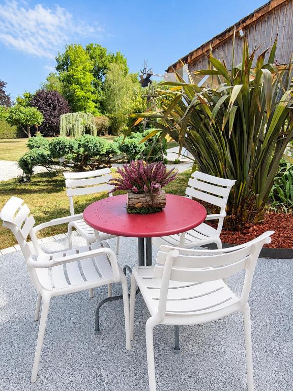 a table with white chairs and a red table with a plant at Gîte de la Lorada in Nouaillé-Maupertuis