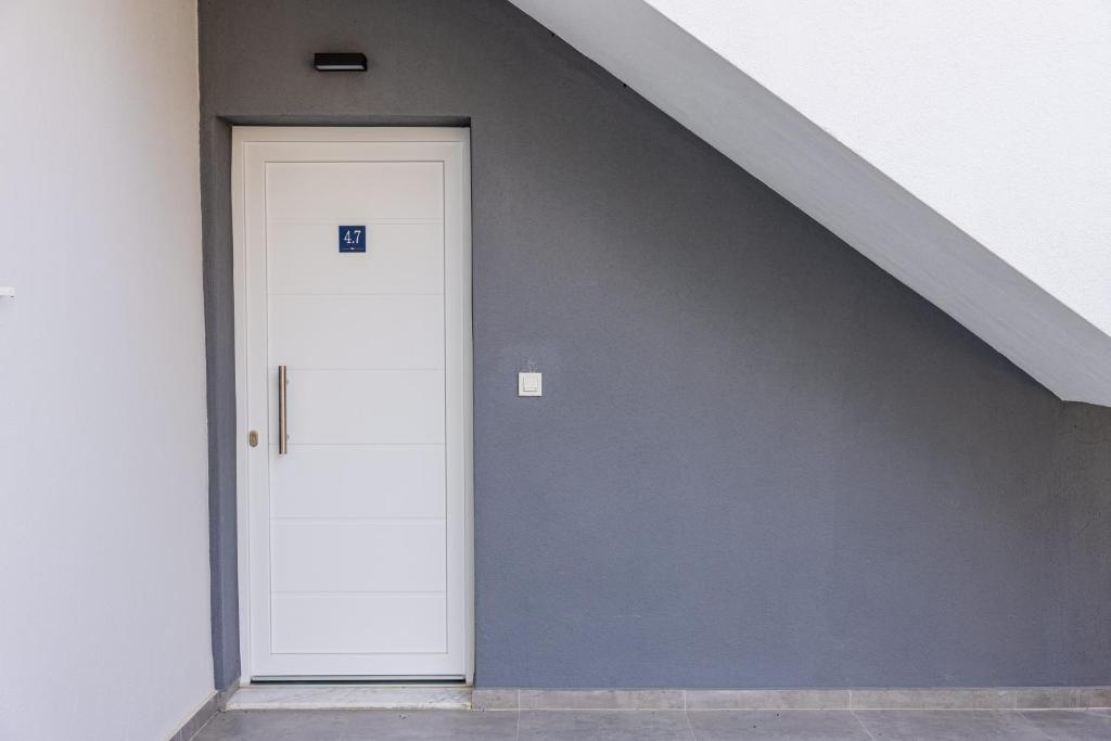 a hallway with a white door and a staircase at Green Almond's Comfort Apartment in Orfánion