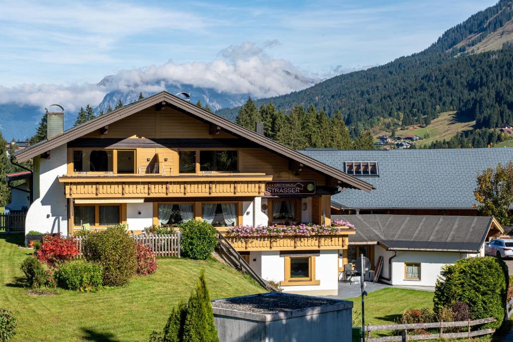 a house on a hill with mountains in the background at Gästehaus Strasser in Riezlern