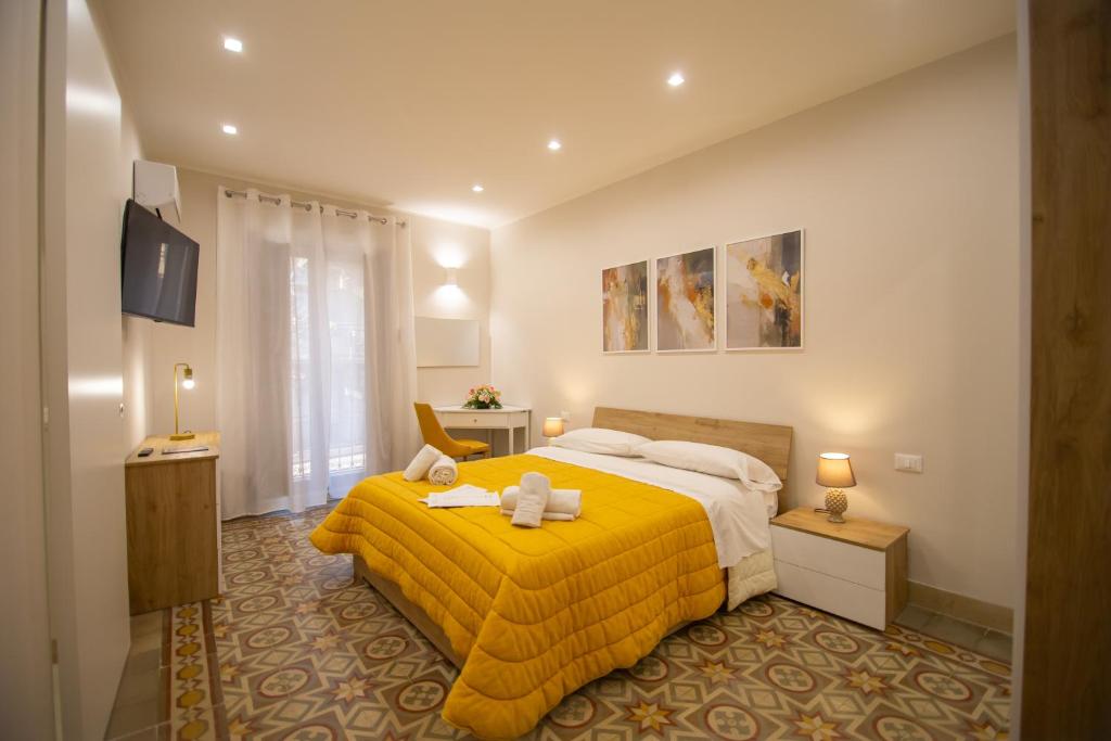 a bedroom with a yellow bed with two stuffed animals on it at Athenèa Smart Rooms - Atenea Collection in Agrigento