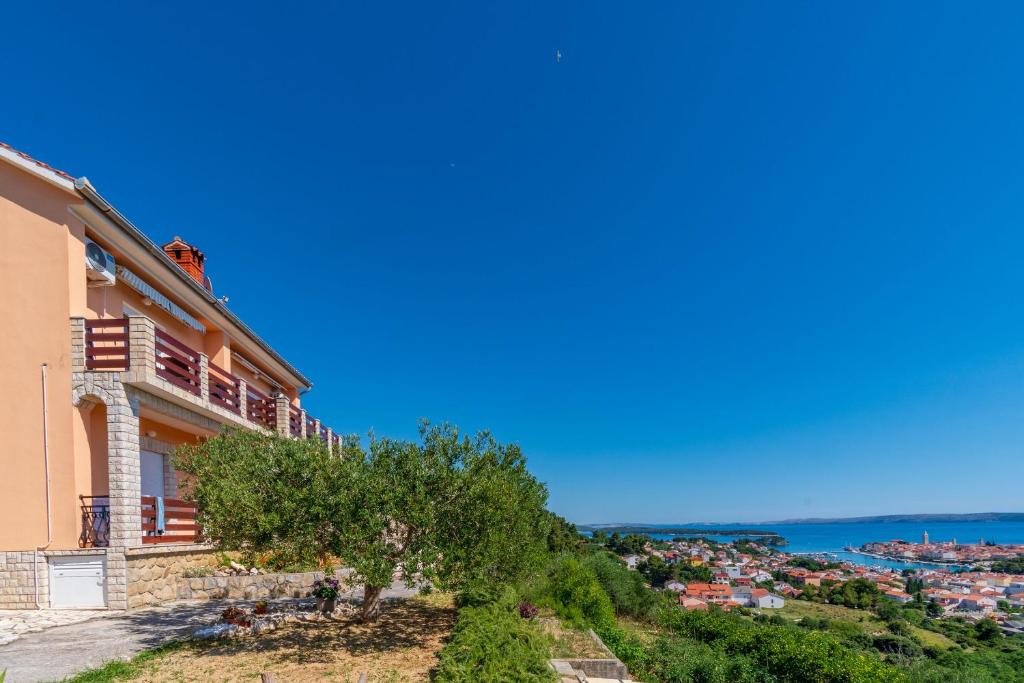 a house on a hill with the ocean in the background at Apartments Andrija in Palit