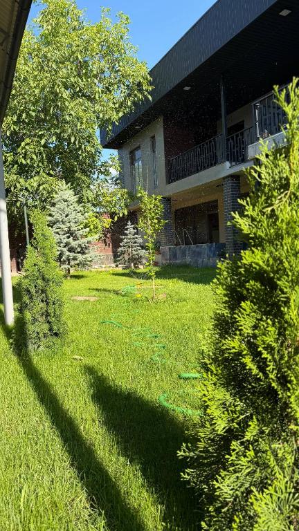 a house with a yard with green grass and trees at Comfort Point Hotel in Bishkek