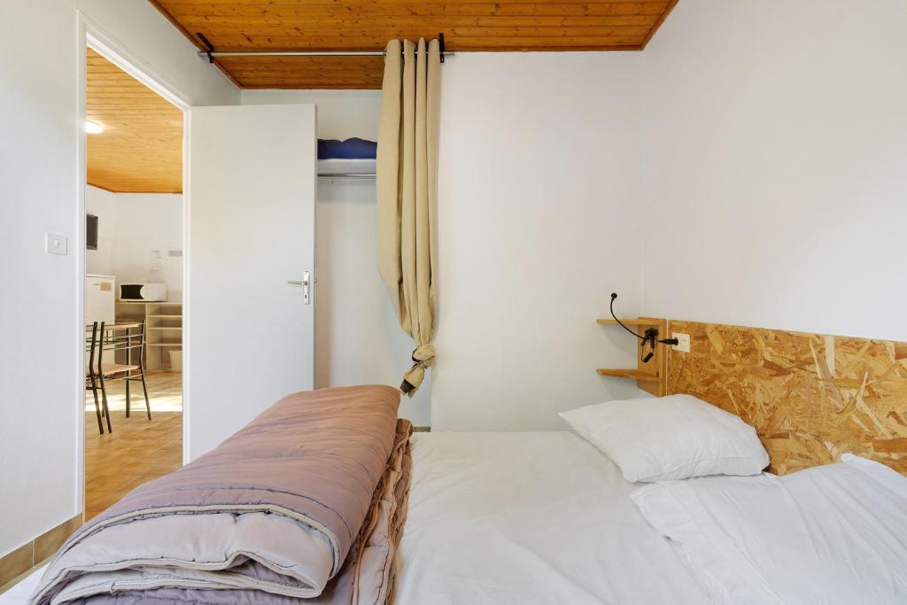 a bedroom with a white bed with a stone wall at 4.Les Chenes option Clim- 4 pers in Calviac