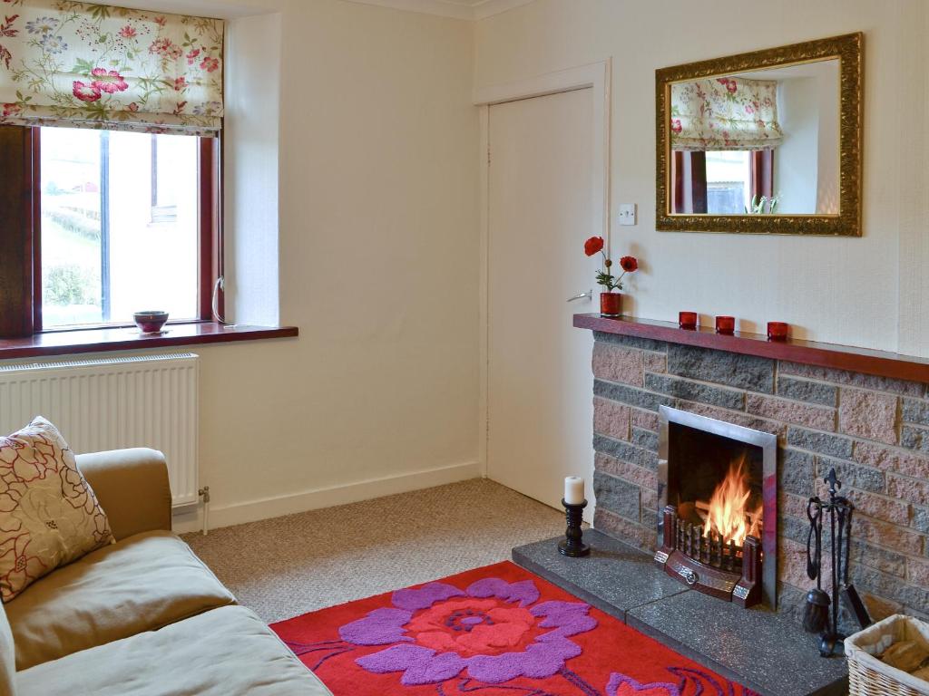 a living room with a fireplace and a couch at Beuchan Cottage Keir Mill in Closeburn
