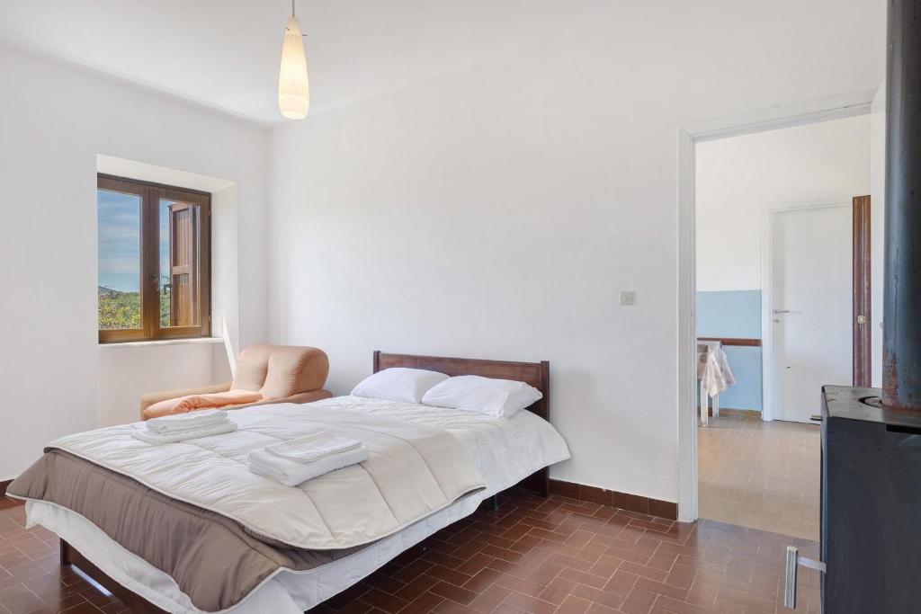 a white bedroom with a large bed and a chair at Le Vallocchie in Concerviano