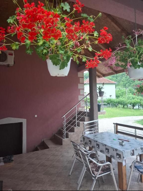 a table and chairs with red flowers hanging from a ceiling at PODNOZJe KOPAONIKA in Brus