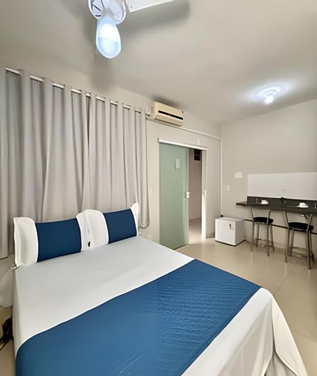 a bedroom with a blue and white bed and a table at Studio #3 Rubi in Campos dos Goytacazes