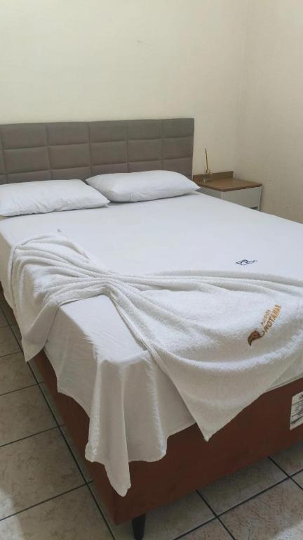 a large bed with a white blanket on it at Pousada Rotamar in Paraipaba