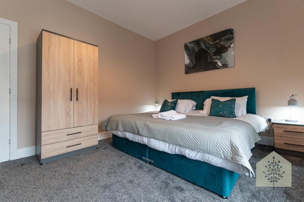 a bedroom with a bed and a wooden cabinet at Fairhurst House in Leigh