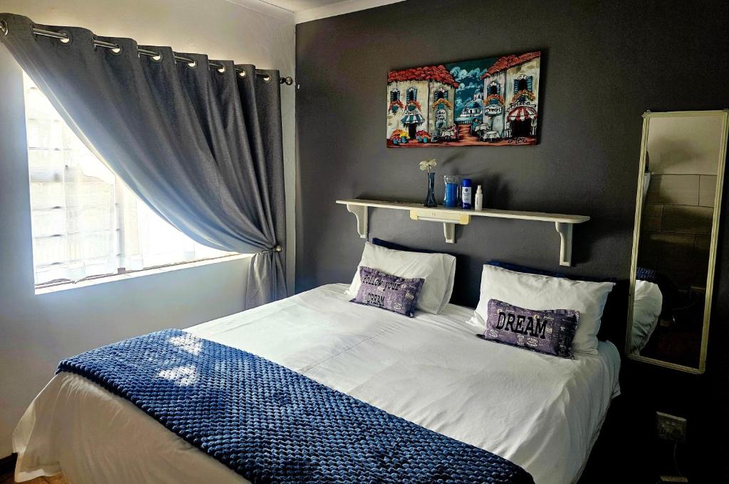 a bedroom with a bed with two pillows and a window at PhysEQFiT Guesthouse in Centurion