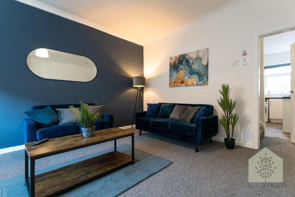 a living room with two blue couches and a table at Holt House in Hindley