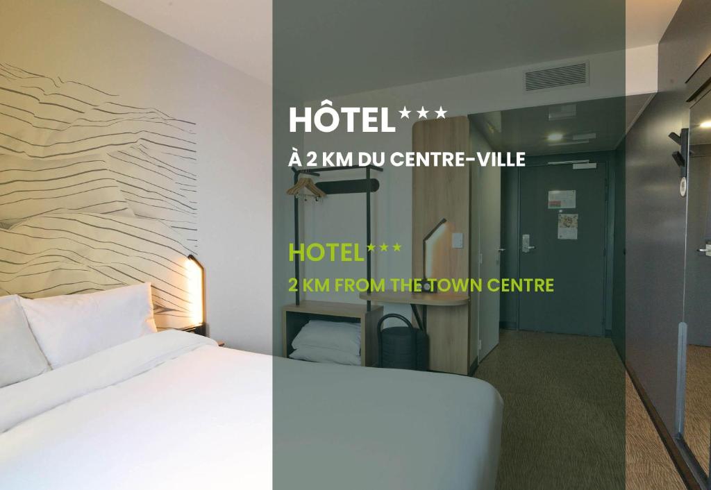 a hotel room with a bed and a sign on the wall at B&B HOTEL Dreux Nord in Dreux
