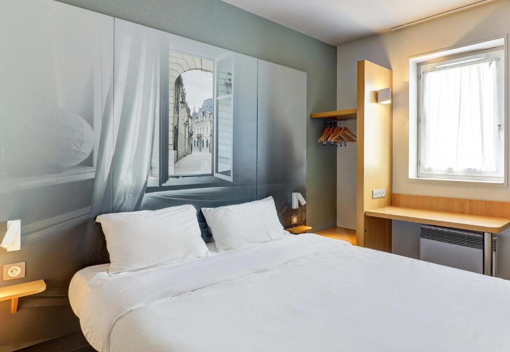 a bedroom with a large white bed and a window at B&B HOTEL Dijon Les Portes du Sud in Marsannay-la-Côte