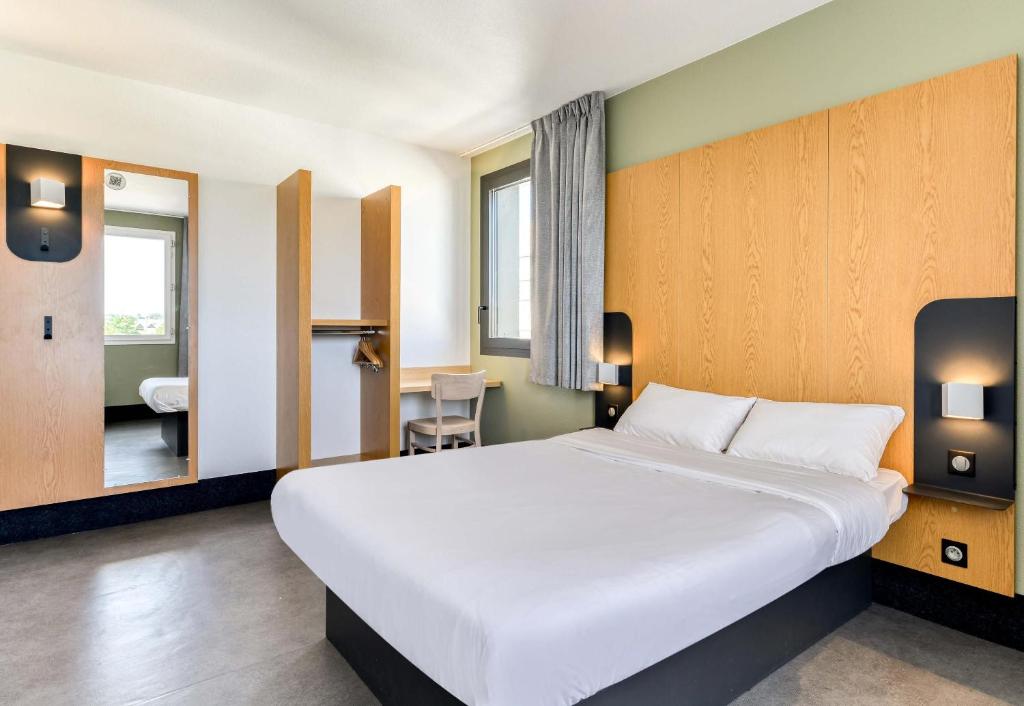 a bedroom with a large white bed and a bathroom at B&B HOTEL Montpellier Centre Le Millénaire 3 étoiles in Montpellier