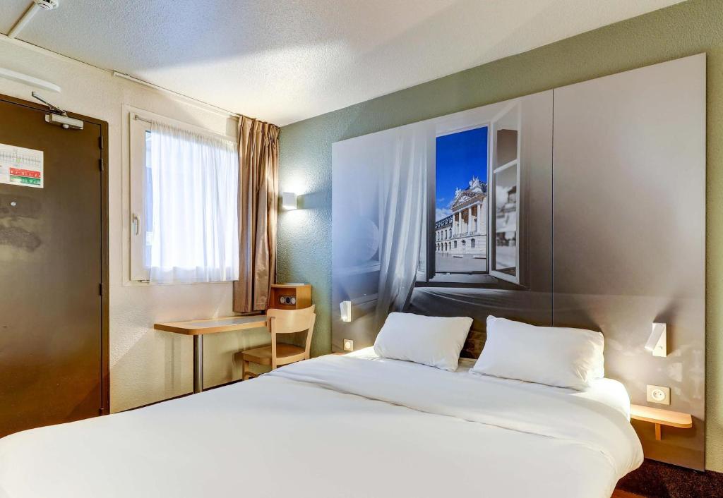 a hotel room with a large bed and a desk at B&B HOTEL Dijon Marsannay in Marsannay-la-Côte