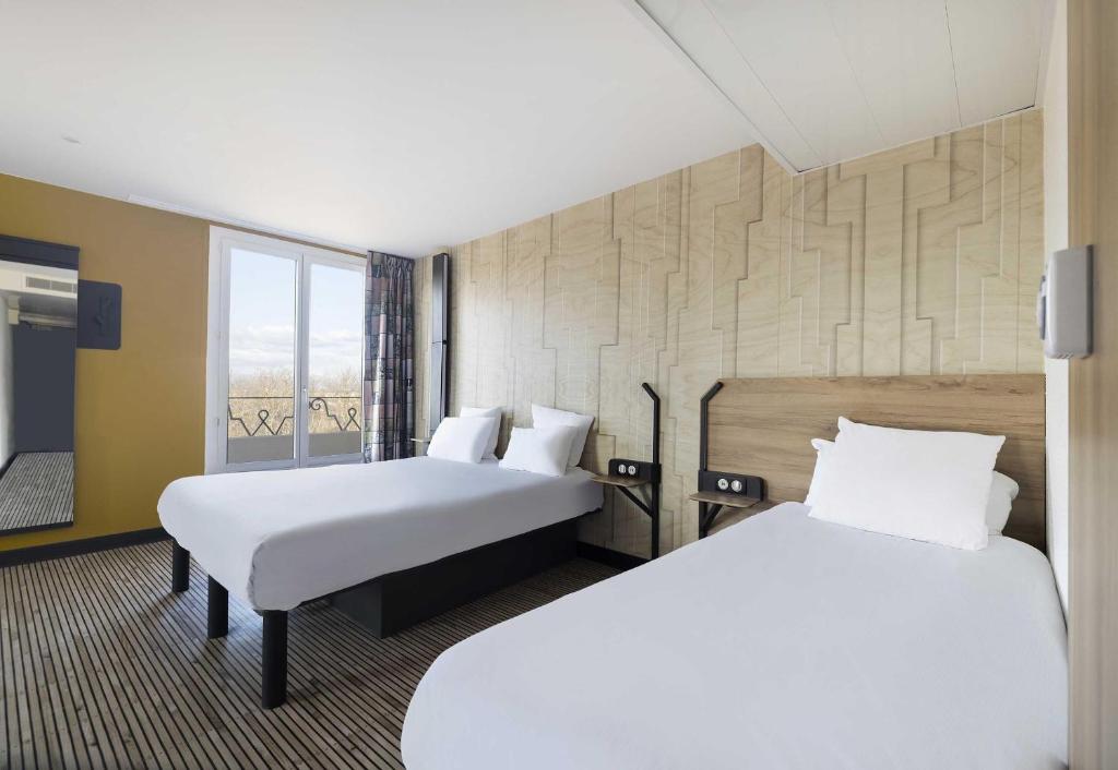 a hotel room with two beds and a window at B&B HOTEL Perpignan Centre in Perpignan