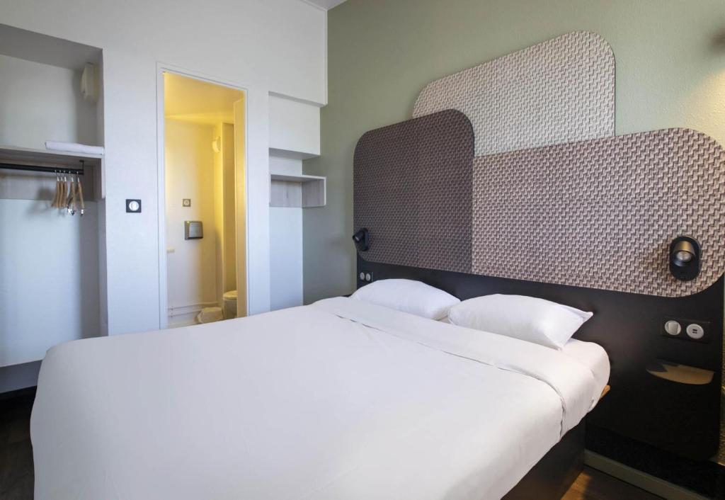 a bedroom with a large white bed in it at B&B HOTEL Avignon 1 in Le Pontet