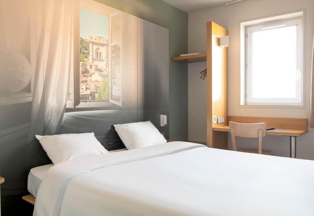 a bedroom with two white beds and a window at B&B HOTEL Avignon 2 in Le Pontet