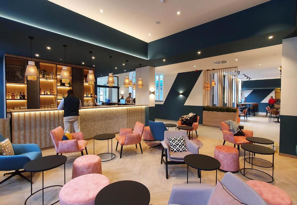 a lobby with chairs and tables and a bar at B&B HOTEL Hasselt in Hasselt