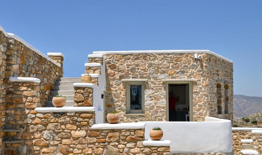a stone building with potted plants on it at Koumaros Cycladic Suites in Koumáros
