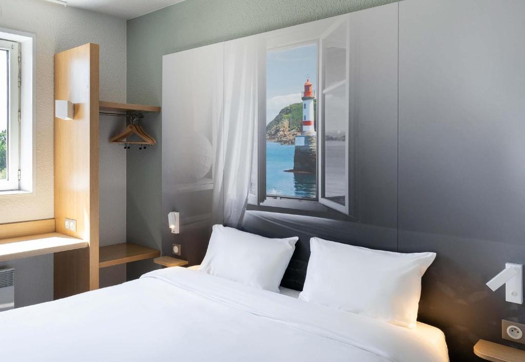 a bedroom with a white bed and a window at B&B HOTEL Lorient Caudan in Caudan