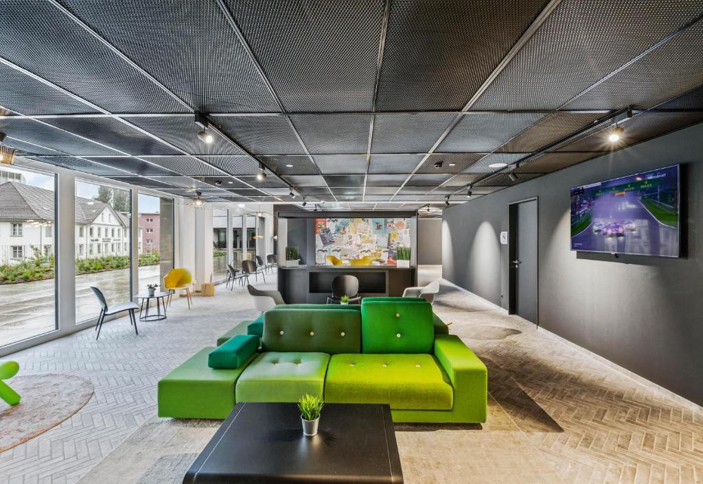 a living room with a green couch and a flat screen tv at B&B HOTEL St Gallen in St. Gallen