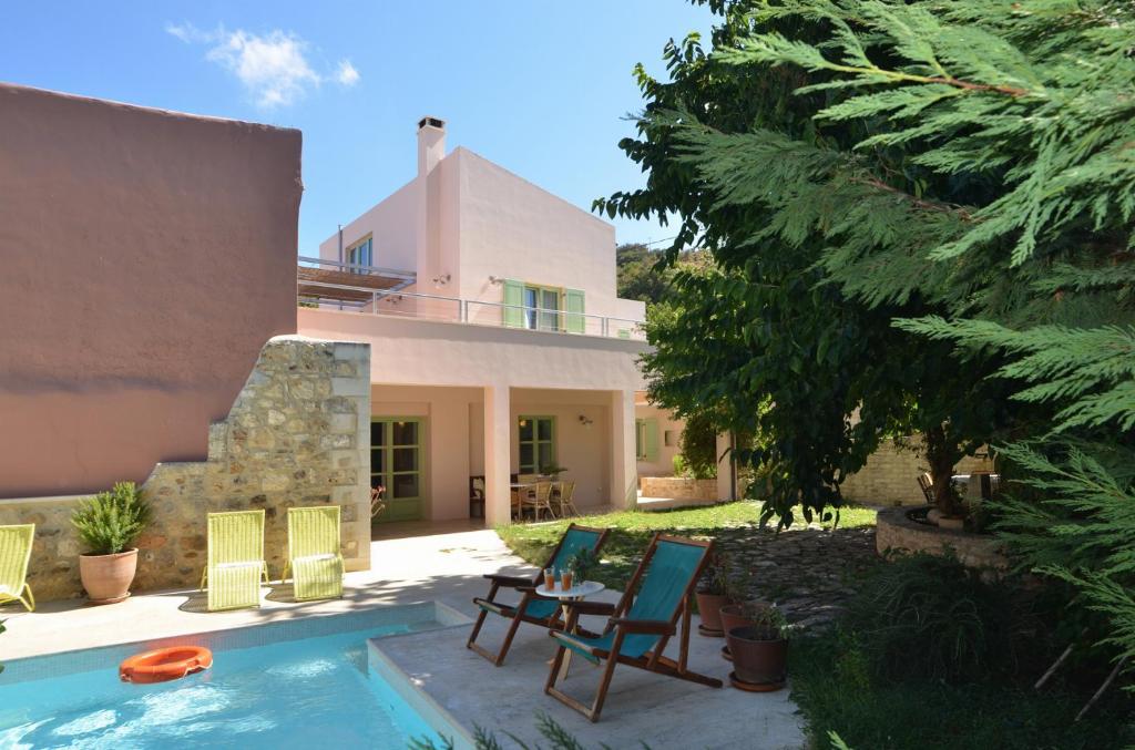 a yard with chairs and a swimming pool in front of a house at Villa Verde Petra in Arménoi