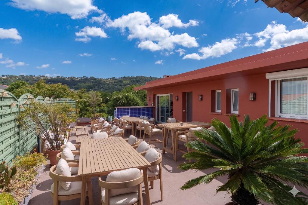 a patio with tables and chairs on a building at Hôtel CASABELLA Cannes Mouans Sartoux in Mouans-Sartoux