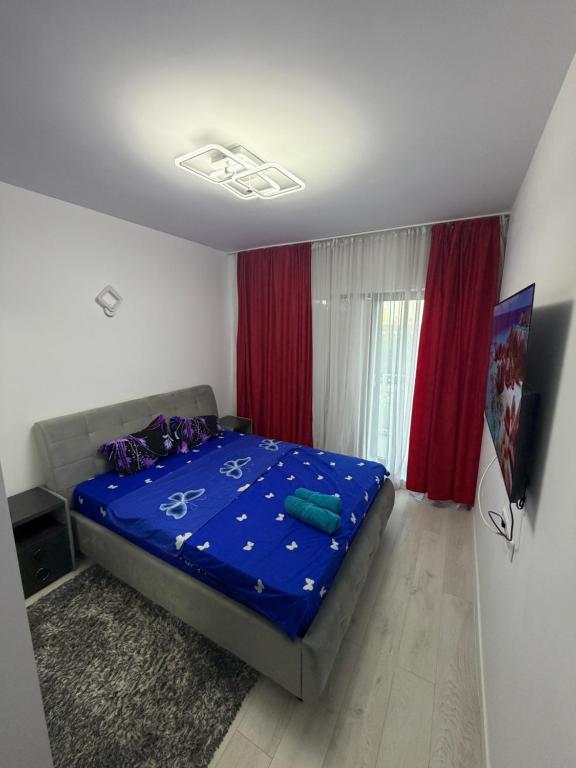 a bedroom with a bed with blue sheets and red curtains at Apartament in Ploiesti 8 in Ploieşti