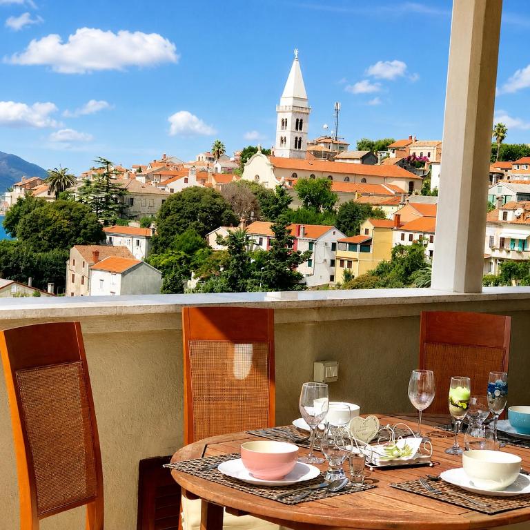 a table with wine glasses and a view of a city at Losinj Panorama Penthouse in Mali Lošinj