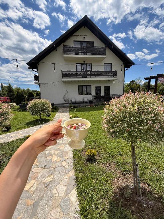 a person holding a bowl in front of a house at Pensiunea Remember Me in Câmpulung