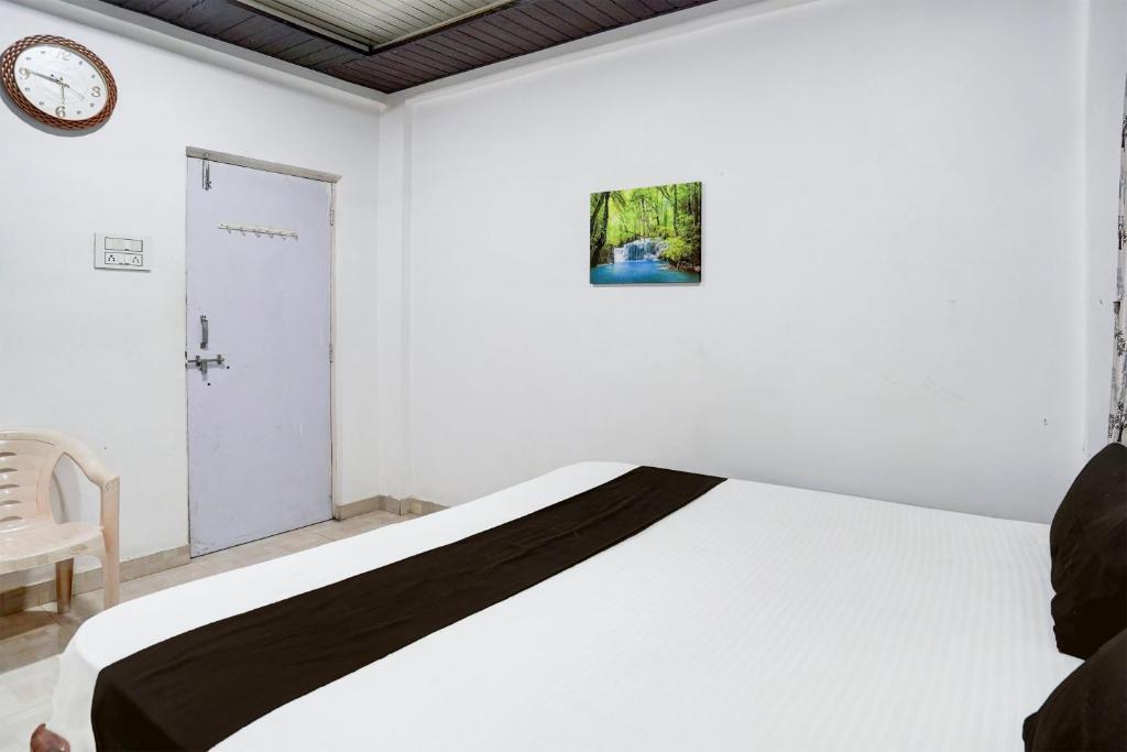 a white bedroom with a bed and a chair at Hotel O Raj Resort in Sopāra