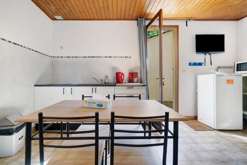 a kitchen with a table and chairs and a refrigerator at 7.Les rossignols option Clim-4 pers in Calviac