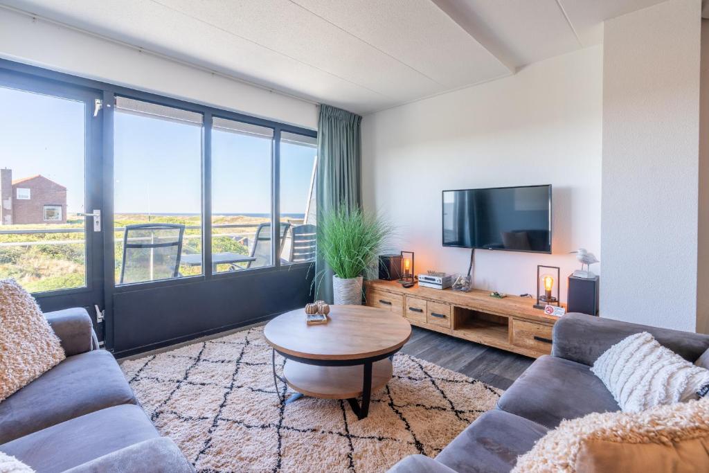 a living room with a couch and a tv and a table at Appartementencomplex Juliana 94 in De Koog
