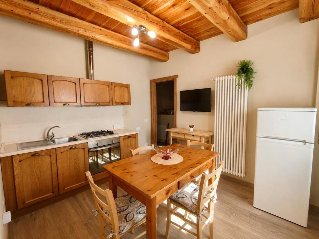 a kitchen with a wooden table and a white refrigerator at Appartamento Alta Valle Maira - Tibert in Ponte Maira