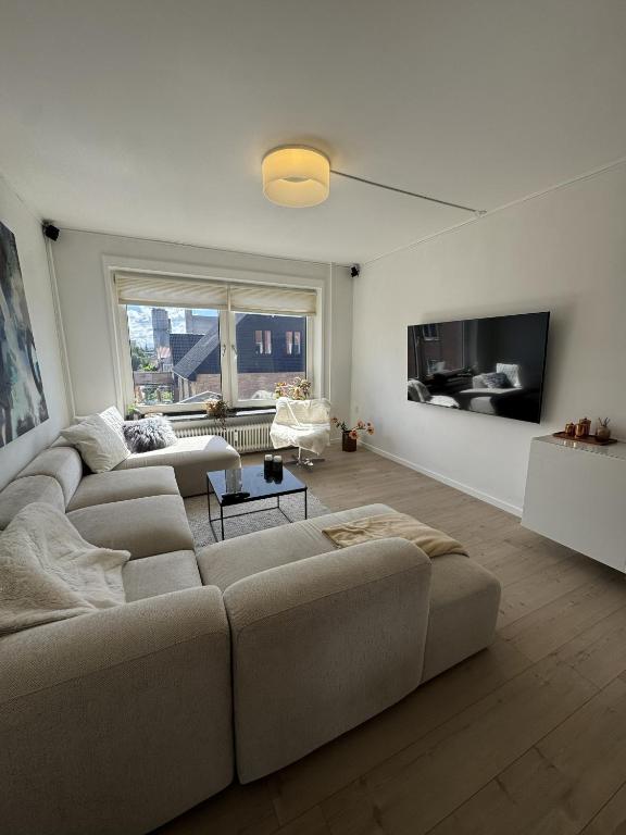 a living room with a couch and a tv at Hygge Home Aalborg, Free Parking & 15 Min to City Centre in Nørresundby