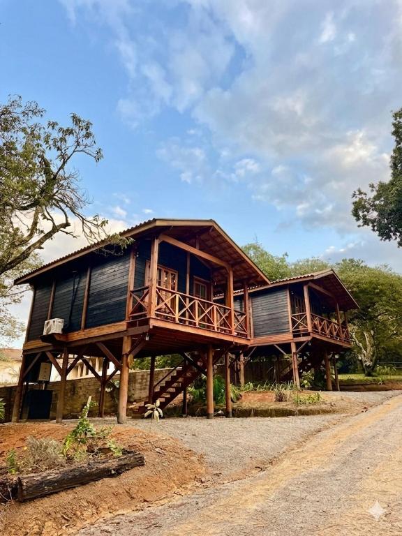 a large wooden house on logs on a road at Cinque chalé in São Roque