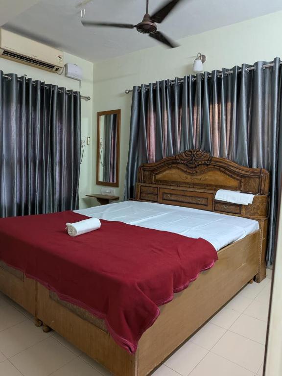 a bedroom with a large bed with a red blanket at walking distance from temble in Guruvāyūr
