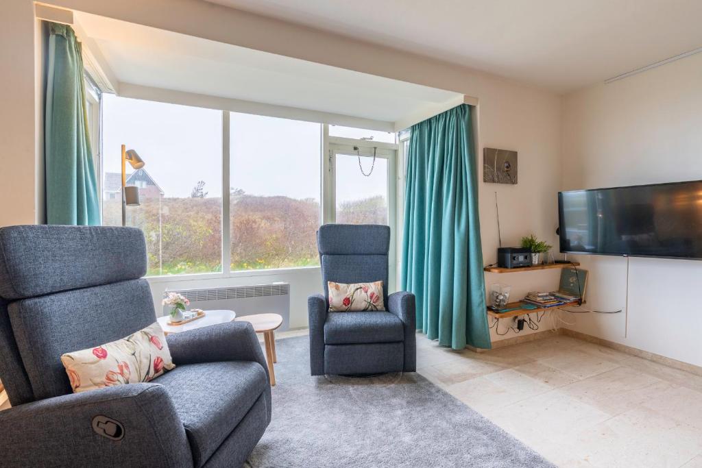 a living room with a couch and a chair and a tv at Appartementencomplex Juliana 68 in De Koog