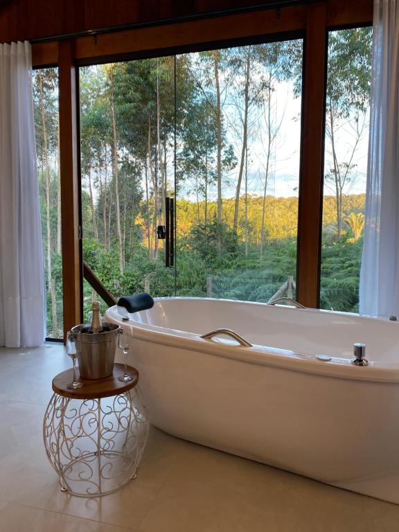 a bath tub in a room with a large window at Chalés Colina dos Colibris in Santa Teresa