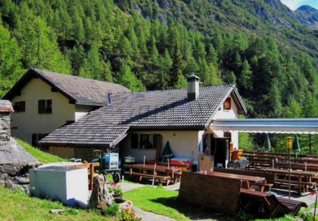 a house with benches in front of a mountain at Capanna Tremorgio in Quinto