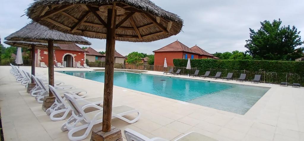 a group of chairs and umbrellas next to a swimming pool at Beau séjour in Prayssac