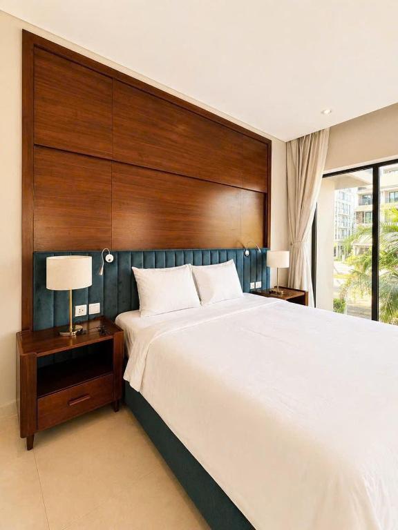a bedroom with a large bed with a wooden headboard at AnHuy Villa in Phú Quốc