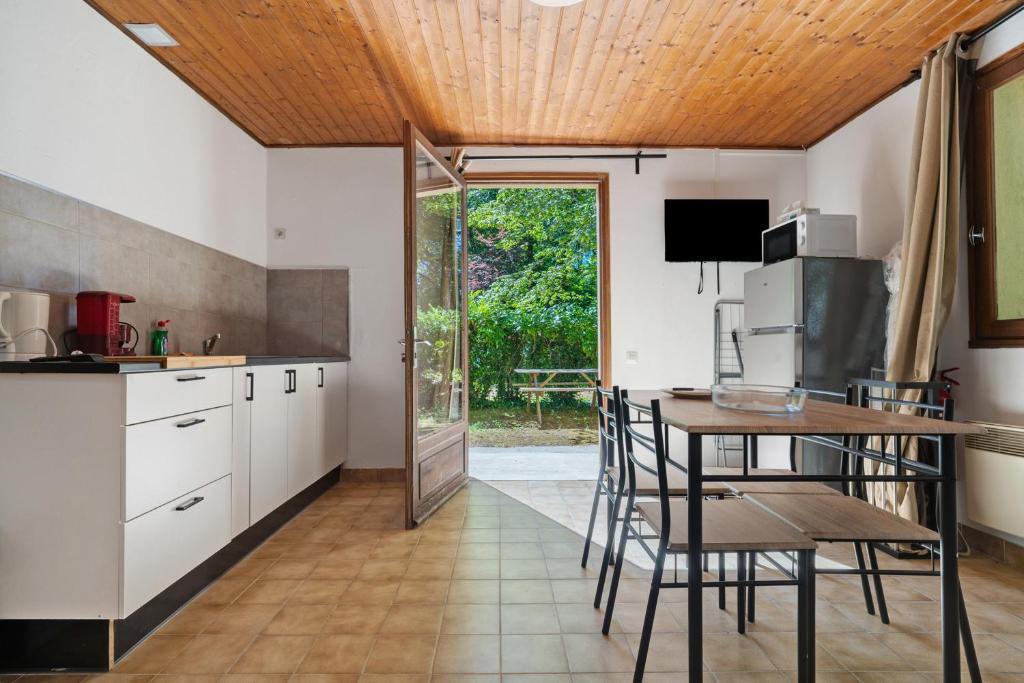 a kitchen with white cabinets and a table with chairs at 10. cerisiers option clim- 4 pers in Calviac
