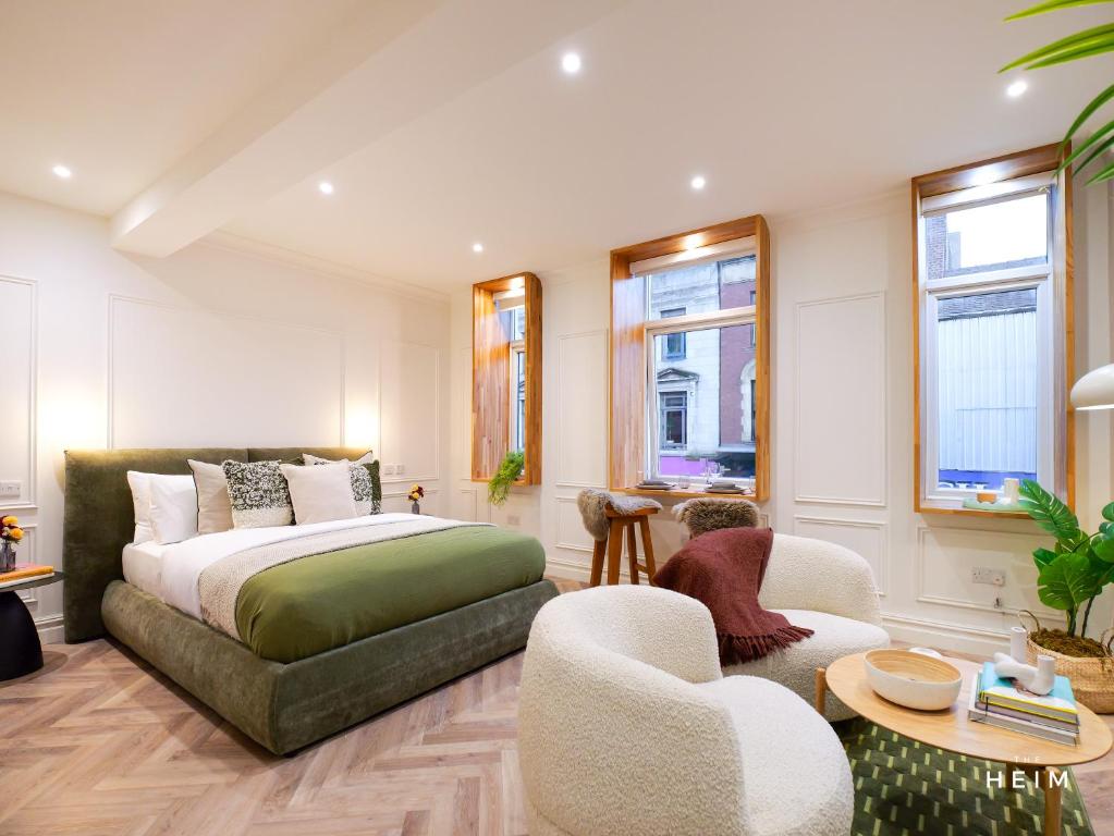 a bedroom with a bed and a couch and chairs at The Heim Aparthotel in Manchester