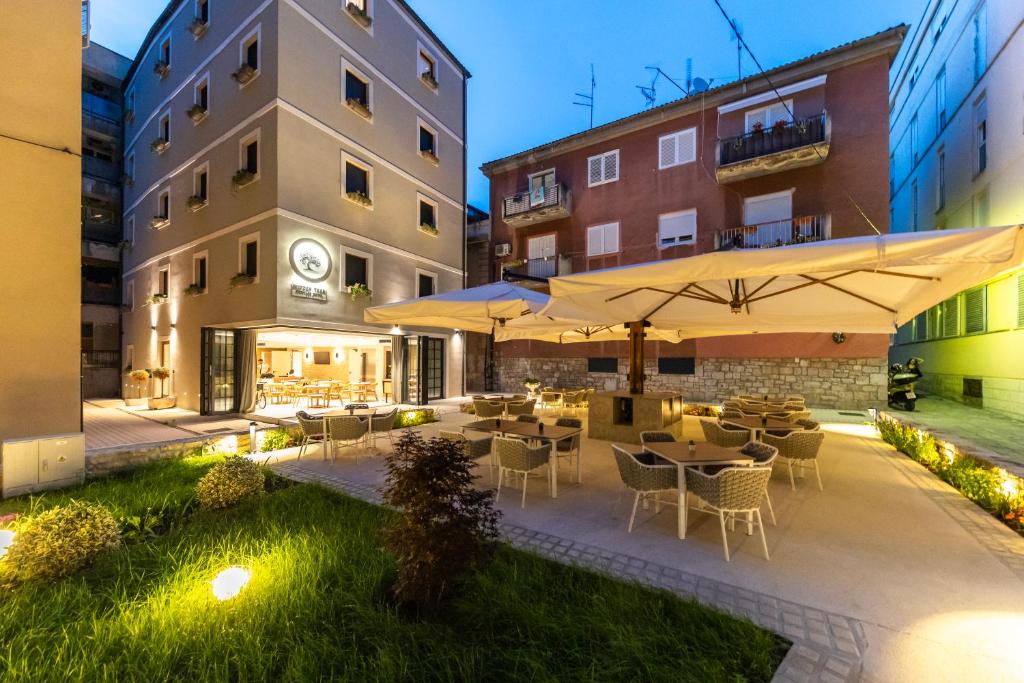 an outdoor patio with tables and chairs and umbrellas at Hidden Tree Heritage Hotel in Zadar