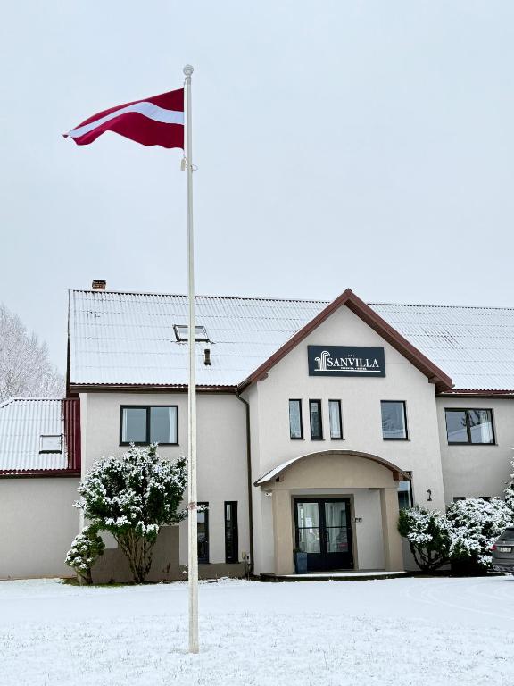 eine Flagge im Schnee vor einem Gebäude in der Unterkunft Hotel Sanvilla in Sigulda