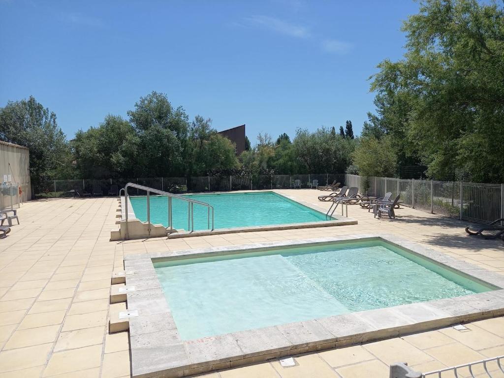a swimming pool in a yard with chairs and a fence at Cottage clim piscine in Saint-Saturnin-lès-Avignon