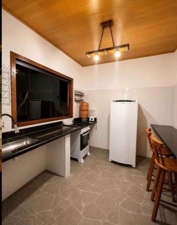 a kitchen with a sink and a refrigerator at Pousada Refúgio Encantado-Cavernas do Peruaçu in Itacarambi
